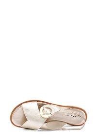 Sandal in metallo dorato con cinturini incrociati, dettaglio della fibbia rotonda in oro, suola piatta e texture liscia. Design leggero per una facile vestibilità.