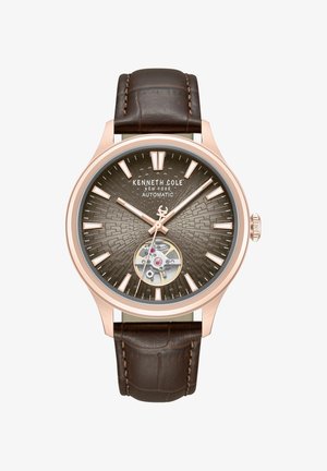 Automatski sat Kenneth Cole s kućištem od ružičastog zlata, teksturiranim smeđim brojčanikom, vidljivim mehanizmom zupčanika i tamnosmeđim kožnim remenom s prošivima.