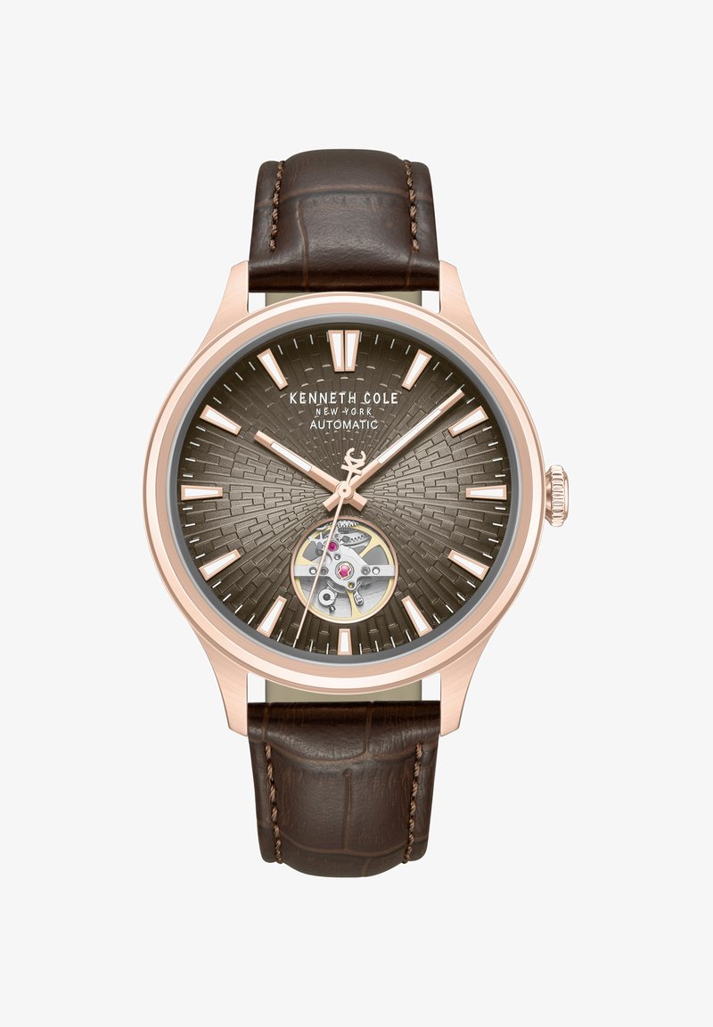 Montre automatique Kenneth Cole avec boîtier en or rose, cadran marron texturé, mécanisme d'engrenages visible et bracelet en cuir marron foncé avec surpiqûres.