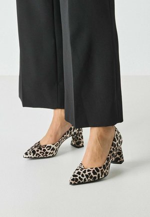 Hohe Schuhe mit Leopardenmuster, spitz zulaufender Zehenpartie und Blockabsatz, mit weicher Textur und glattem Stoff. Kombiniert mit schwarzen, weit geschnittenen Hosen.