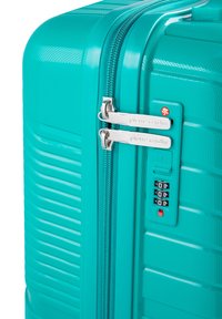Valigia rigida turchese con superficie texture, doppi zip argentati, lucchetto a combinazione e strisce orizzontali rialzate per una migliore presa.