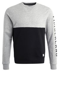 Grijze en zwarte sweatshirt met een raglanontwerp, ronde hals en "TIMBERLAND" verticaal gedrukt op de mouw. Zachte, gestructureerde stof.