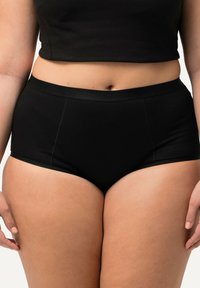 Mutande nere a vita alta con texture di tessuto liscia, fascia elasticizzata e dettagli di cucitura minimalista.