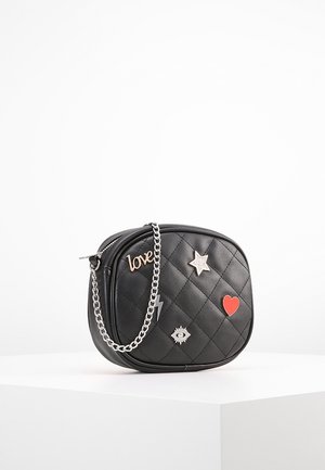 Musta tikattu olkalaukku hopeisella ketjuhihnalla ja koristepinneillä, mukaan lukien "love", tähti, silmä, salamanisku ja punainen sydän.