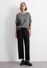 Γκρι πουλόβερ με στρογγυλή λαιμόκοψη, χαλαρή εφαρμογή και ριμπ μανίκια. Μαύρα παντελόνια με ελαστική μέση και ίσια γραμμή. Μαύρα κορδόνια παπούτσια.