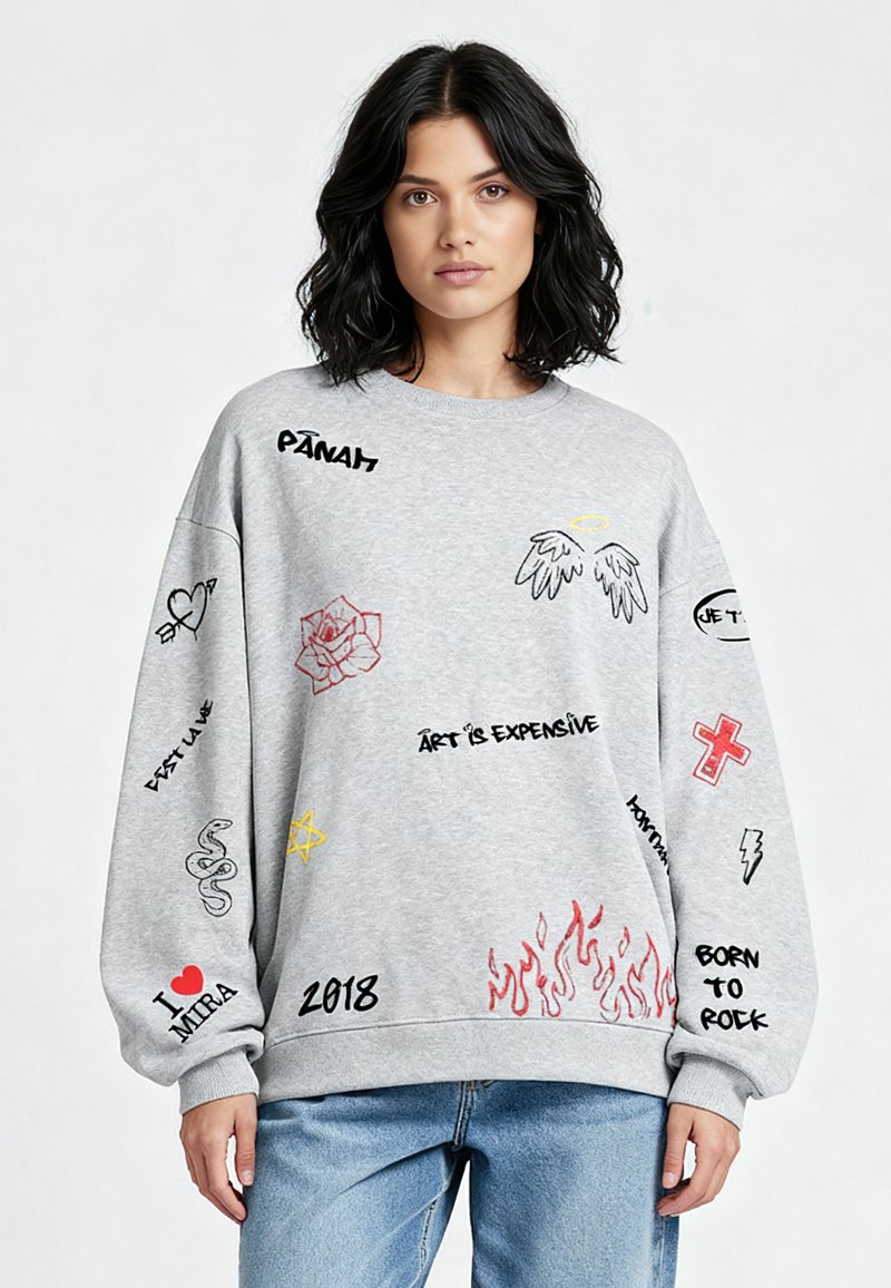 Felpa grigia oversize con diverse grafiche ricamate, tra cui una rosa, ali e frasi di testo in nero, rosso e giallo.