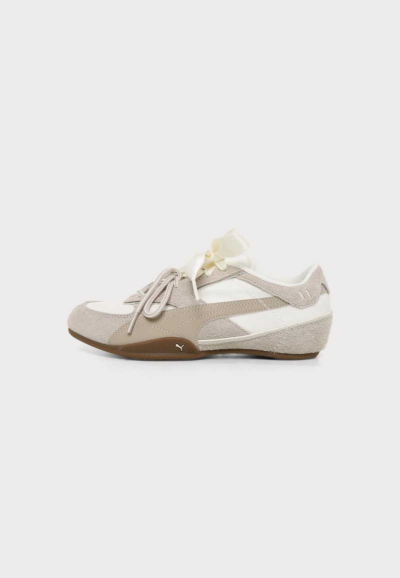 Baskets blanches et beiges à profil bas avec des détails en daim, fermeture à lacets et un petit logo Puma sur le côté de la semelle en caoutchouc marron.