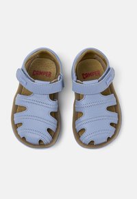 Ljust blå läder sandaler med en remdesign, beige innersulor och kardborrestängning, med utskurna mönster och kontrasterande sömmar.