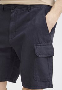 Mørk marineblå cargo shorts laget av lett stoff, med side lommer, knappelukking og synlige søm detaljer.
