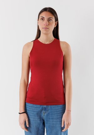 Top rosso senza maniche in un materiale morbido ed elastico con collo rotondo; abbinato a jeans in denim blu. Design semplice e aderente senza motivi.