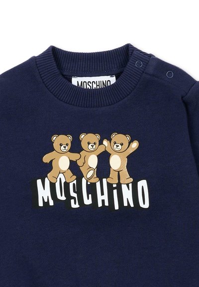 Granatowy sweter dla malucha z trzema tańczącymi misiami nad nazwą marki "MOSCHINO" w białych dużych literach.