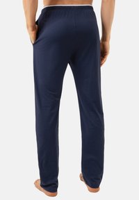 Donkerblauwe loungebroek gemaakt van zacht materiaal met een elastische tailleband, zijzakken en een rechte pijp.