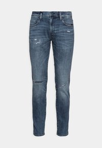 Vaqueros de denim azul ajustados con un lavado descolorido y sutiles detalles desgastados en los muslos y las rodillas, que cuentan con un estilo clásico de cinco bolsillos.