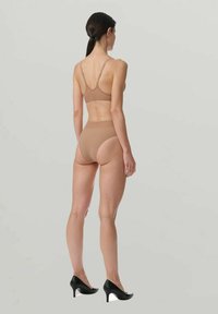 Reggiseno seamless color nocciola e culotte high-waisted. Tessuto morbido, spalline regolabili e design minimalista. Abbina con tacchi neri, texture liscia.