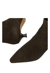 Hnědé semišové kotníkové boty s špičatou špičkou a zakřiveným dřevěným podpatkem, s minimalistickým designem a tlumenou texturou bez ozdob.