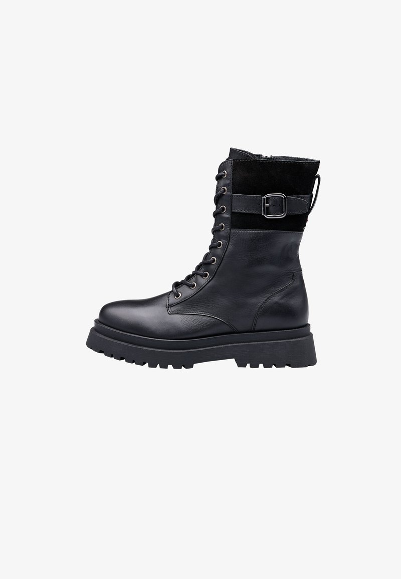 Czarny skórzany botek do kostki z masywną gumową podeszwą, wyściełanym kołnierzem i zasuwany z przodu na sznurówki. Z boku ozdobiony klamrą dla dodatkowego efektu.