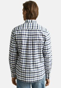 Herrenlangarmhemd im karierten Muster mit weißen und dunkelblauen Quadraten. Baumwollstoff, Button-Down-Kragen und Manschetten mit einem Knopf.