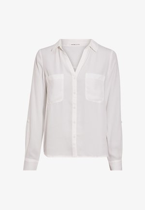 Blusa bianca a maniche lunghe con colletto, dotata di due taschini sul petto e bottoni sul davanti. Realizzata in un tessuto leggero e morbido.