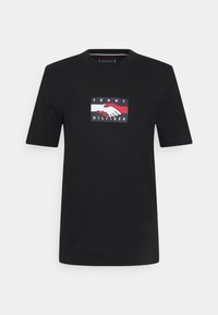 Černé bavlněné tričko s obdélníkovou grafikou s červenými a bílými prvky, zobrazením podání ruky a textem "TOMMY HILFIGER".