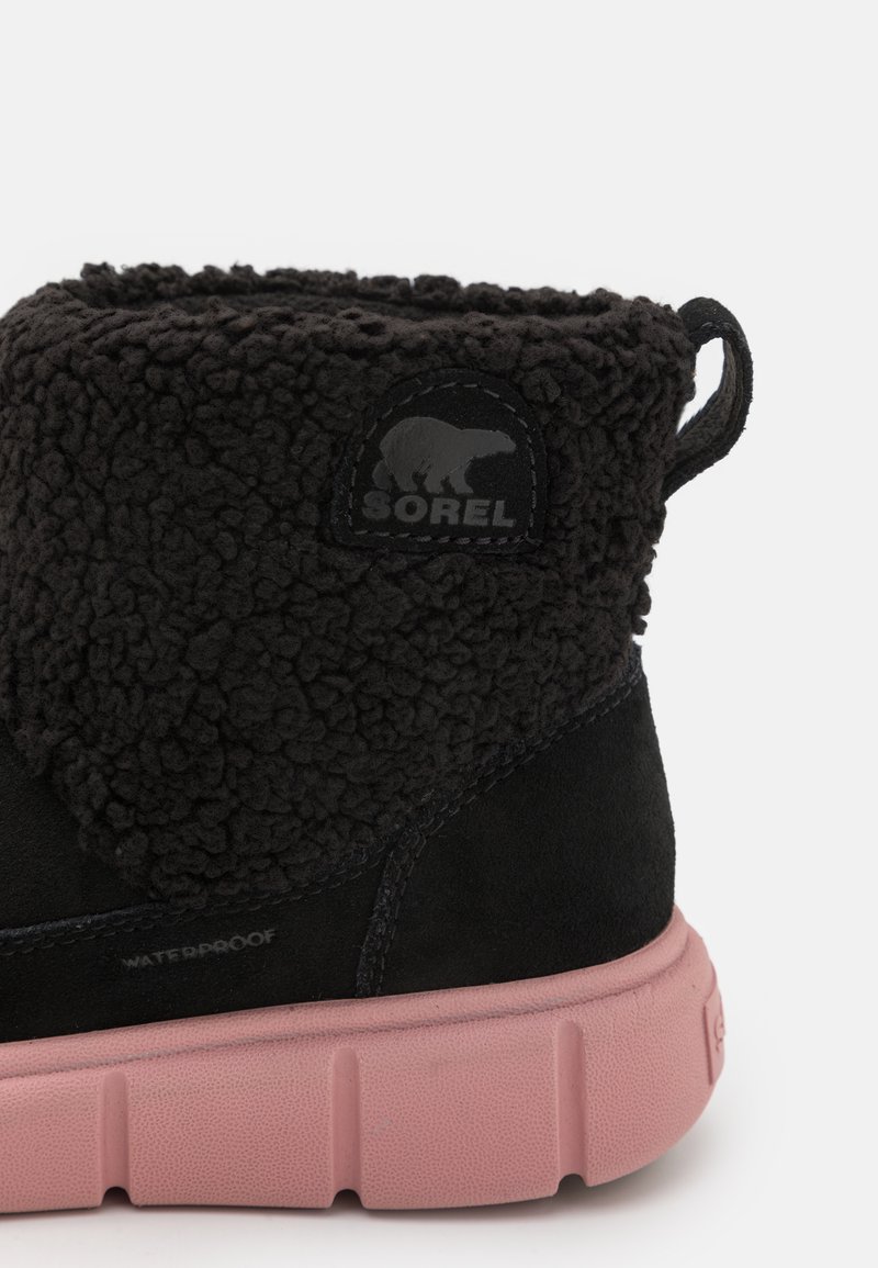 Schwarze wasserdichte Stiefel mit einem flauschigen Fellkragen, einer gummierten pinken Sohle und einem Sorel-Logo-Patch. Ausgestattet mit strukturiertem Stoff und glattem Wildleder.