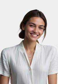 Hvid, kortærmet bluse med vertikale striber og krave. Et sølvfarvet hjerteformet halskæde er båret om halsen.