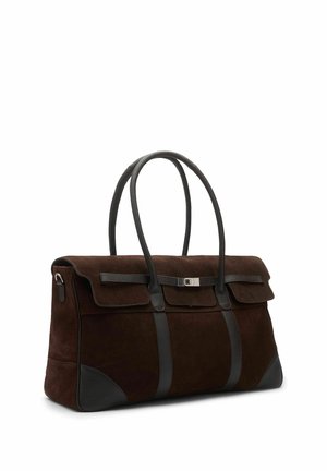 Sac à main en daim marron foncé avec deux longues anses en cuir noir, des renforts en cuir noir aux coins et un rabat avant avec une petite boucle de fermeture.