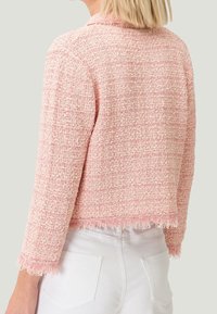 Giacca rosa con texture, orlo a frange, maniche a tre quarti e design aperto, realizzata in un materiale tessuto leggero.