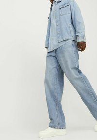 Hellblaue Jeansjacke mit zwei Fronttaschen und Druckknöpfen, kombiniert mit passenden hellblauen Jeans und weißen Sneakern.