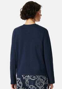 Marinblå långärmad sweatshirt med rund halsringning, mjukt tyg och avslappnad passform, i kombination med mönstrad väv vid fållen.