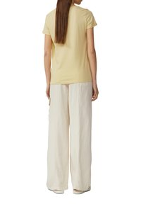 Lichtgele katoenen t-shirt met korte mouwen, gecombineerd met losse, crème-kleurige broeken met zijzakken en een gestructureerde stof.