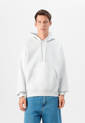Helltaußer Kapuzenpullover aus weichem Stoff, mit einer Kängurutasche und Kordelzug, kombiniert mit lässigen Denim-Jeans.