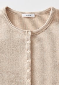 Beige gerippter Cardigan mit rundem Ausschnitt, Knopfverschluss und subtiler Textur. Verfügt über sechs hellfarbige Knöpfe und ein gewebtes Etikett.