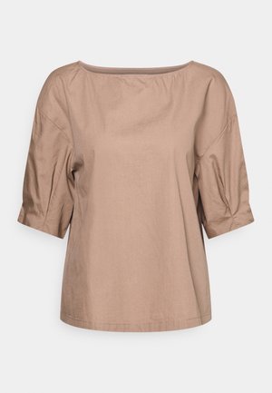 Beige, loszittende damesblouse met ellebooglange mouwen en een brede, afgeronde halslijn, getoond tegen een witte achtergrond.