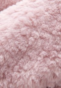Textile rose, moelleux avec une surface douce et texturée. Présente des fibres denses et touffues créant une apparence chaleureuse. Idéal pour la chaleur et le confort.
