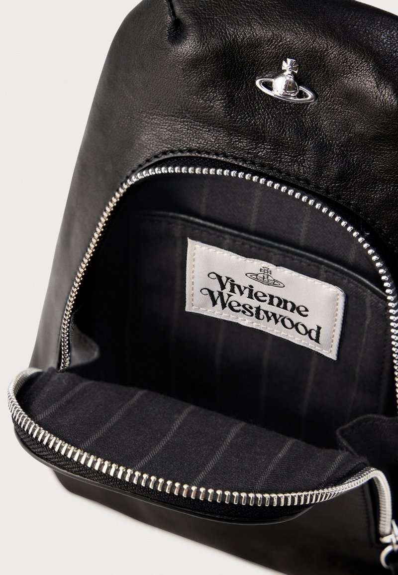 Black leather bag interior featuring a silver zipper, striped fabric lining, and a label reading "Vivienne Westwood." Silver hardware detail visible.