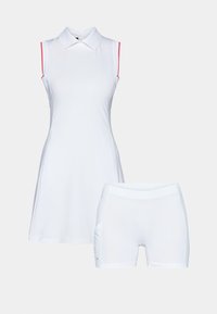 Vit ärmlös klänning med krage, med rosa accenter på axlarna, kombinerad med korta vita shorts. Tillverkad av ett mjukt och lätt tyg.