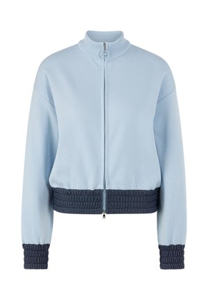 Hellblaue Jacke mit Reißverschluss, geripptem hohem Kragen, dunkelblauen strukturierten elastischen Bündchen und Bund sowie abfallenden Schultern.