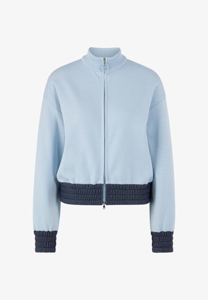 Hellblaue Jacke mit Reißverschluss, geripptem hohem Kragen, dunkelblauen strukturierten elastischen Bündchen und Bund sowie abfallenden Schultern.