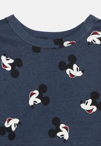 Temno modra bombažna majica s posadskim ovratnikom, z vzorci glav Mickey Mousea v črni, beli in rdeči barvi. Gladek otip.