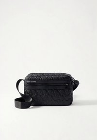 Juoda dirbtinės odos rankinė per petį su tekstūruotu geometriniu raštu, turinti priekinių užtrauktukų kišenę ir reguliuojamą dirželį. Matomas „Armani Exchange“ logotipas.