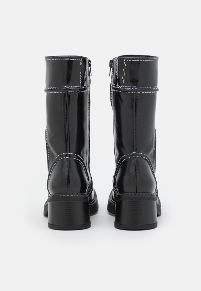 Zwarte patenten leren kniehoge laarzen met witte stiksels, vierkante hakken en zijritsen, met een gladde oppervlakte en gestructureerd ontwerp.