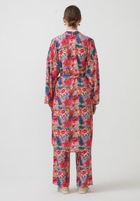 Květinový kimono set s živě růžovým základem a červenými a modrými květinovými vzory. Volný střih s širokými rukávy a odpovídajícími kalhotami.