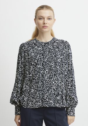 Blusa a righe in bianco e nero con scollatura rotonda, maniche lunghe a sbuffo e dettagli plissettati sul davanti. Tessuto morbido.