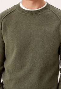 Grüner Strickpullover mit rundem Ausschnitt, gerippten Bündchen und Schulternähten. Das Material wirkt weich und strukturiert, geeignet für die Freizeit.