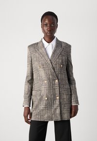 Doppelt knopfgeschlossener Blazer aus einem strukturierten grauen Stoff mit goldenen Knöpfen, ausgestattet mit einem spitzen Kragen, seitlichen Taschen und strukturierten Schultern.