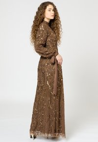 Lange bruine avondjurk van versierd stof met pailletten, met lange mouwen, een getailleerde taille en een bijpassende riem.