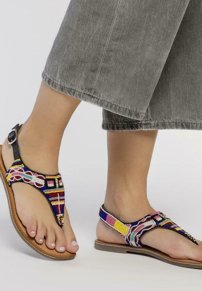 Sandalias de cuentas con patrones multicolores, correas de cuero negras y una suela marrón; el diseño incluye un separador de dedos y soporte para el tobillo.