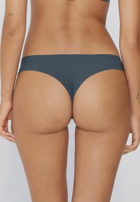 Ciemnoszare majtki bikini o gładkiej fakturze, niskim stanie i minimalnym zakryciu, podkreślające bezszwowe wykończenie.