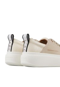 Sneaker beige con tomaia in pelle texturizzata, suola platform bianca e linguette a contrasto con dettagli del logo.