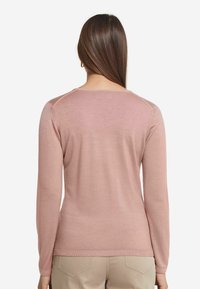 Långärmad, ljusrosa tröja med mjuk struktur, ribbad nederkant och krage. Har en enkel, avslappnad design med en figurnära passform.